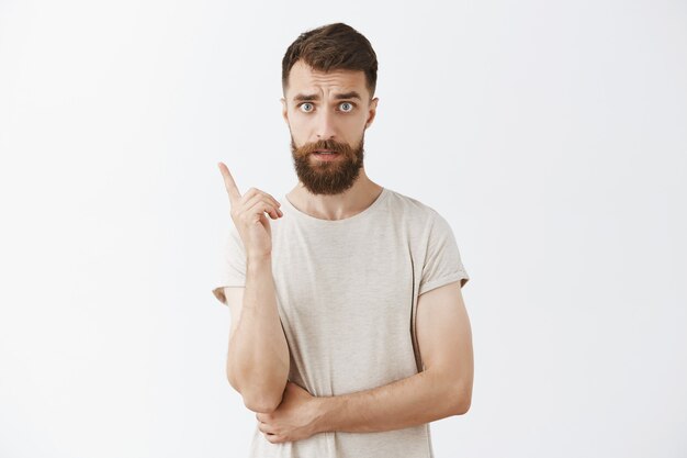 Handsome bearded bearded man posing against the white wall