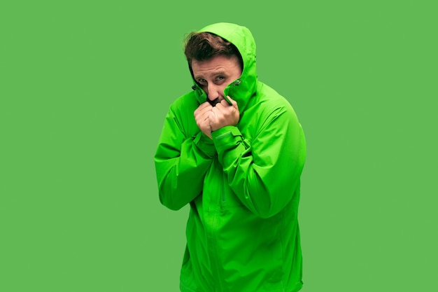 Handsome bearded freezing young man isolated on vivid trendy green color at studio