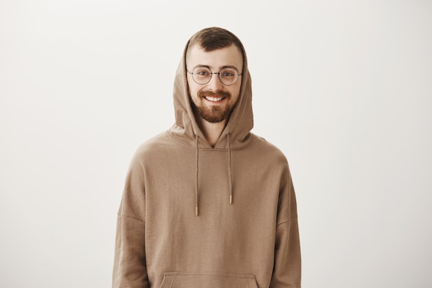 Handsome bearded hipster guy in hoodie and glasses smiling