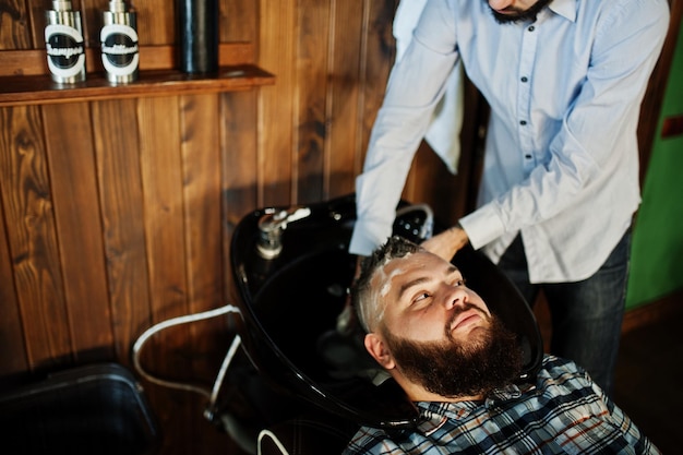 Free photo handsome bearded man at the barbershop barber at work washing head