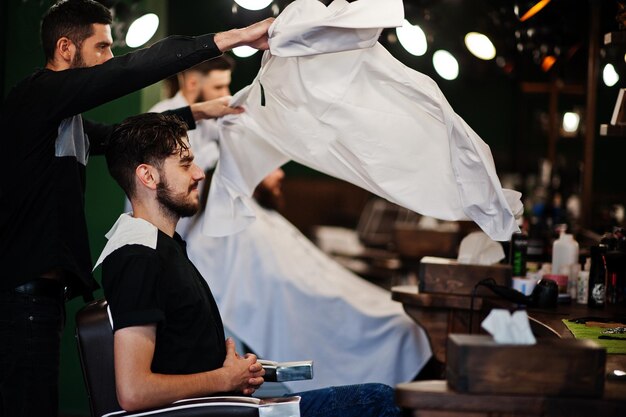 Handsome bearded man at the barbershop barber at work