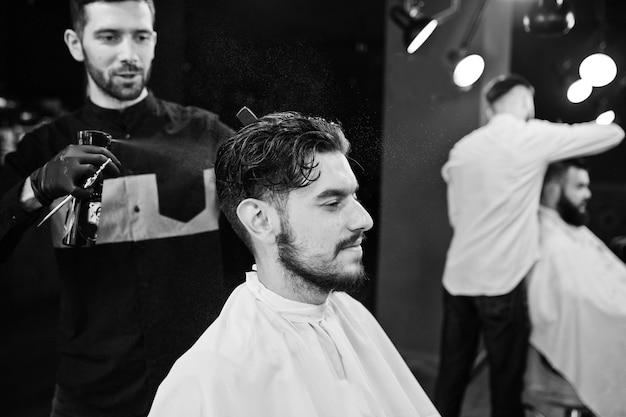 Handsome bearded man at the barbershop barber at work