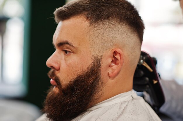 Handsome bearded man at the barbershop barber at work