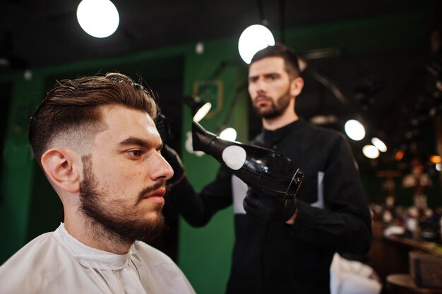 Handsome bearded man at the barbershop barber at work