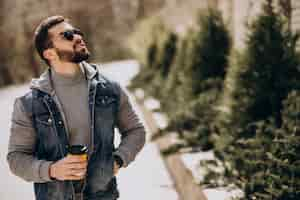 Free photo handsome bearded man drinking coffee outside the street