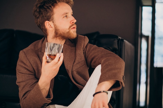 Красивый бородатый мужчина пьет виски