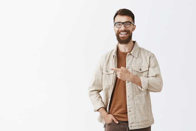 Handsome bearded man in glasses posing against the white wall