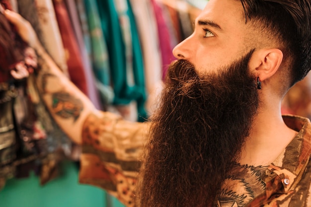 Free photo handsome bearded man shopping in clothes store