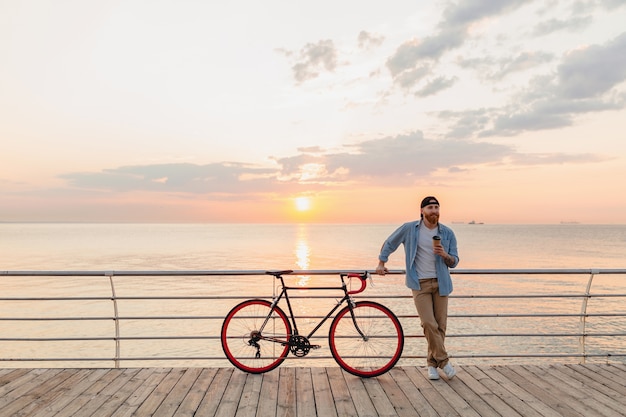 無料写真 コーヒーを飲みながら朝日、自転車で旅行するハンサムなひげを生やした男、健康的なアクティブなライフスタイルの旅行者