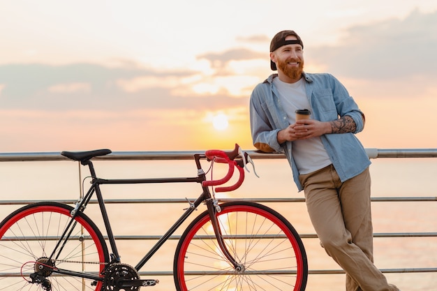 커피를 마시는 바다로 아침 일출에 자전거로 여행하는 잘 생긴 수염 난 남자, 건강한 활동적인 라이프 스타일 여행자