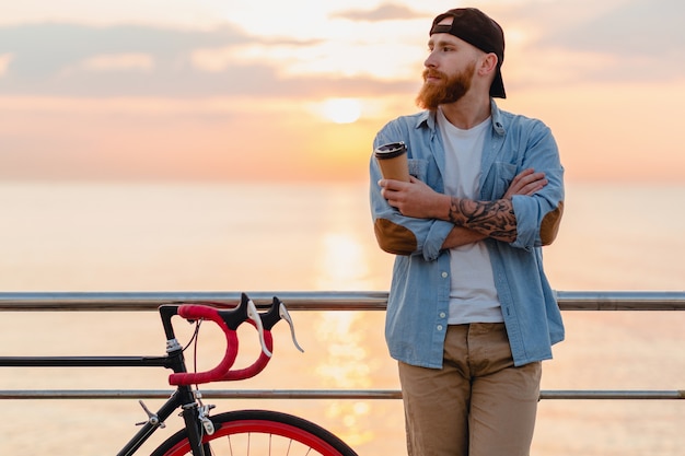 コーヒーを飲みながら朝日、自転車で旅行するハンサムなひげを生やした男、健康的なアクティブなライフスタイルの旅行者