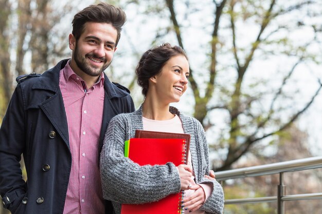 Handsome bearded man walking onthe street with hisgirl-friend who is holding documents and files during autumn weather.