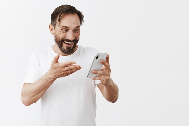 Красивый бородатый зрелый мужчина позирует со своим телефоном