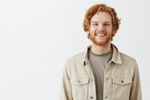 Free photo handsome bearded redhead guy posing against the white wall