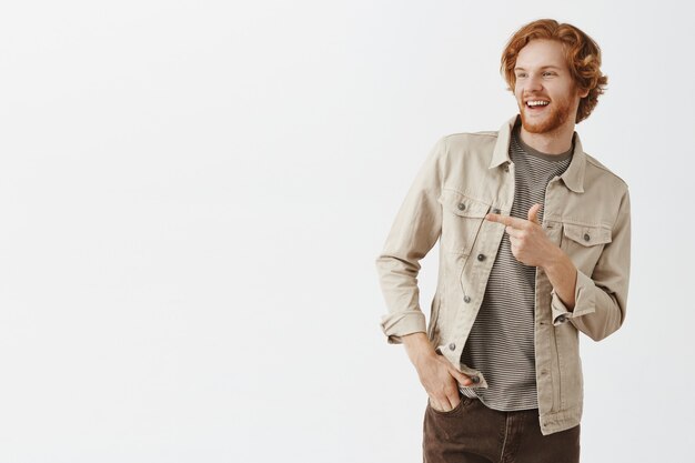 Handsome bearded redhead guy posing against the white wall