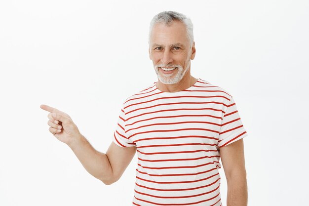 Handsome bearded senior man pointing finger left, showing advertisement