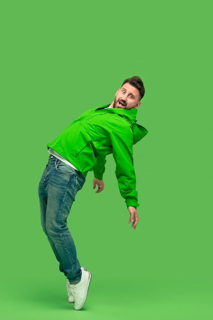 Free photo handsome bearded smiling happy young man looking at front isolated on vivid trendy green studio