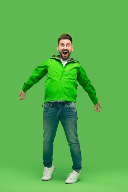 Handsome bearded smiling happy young man looking at front isolated on vivid trendy green studio