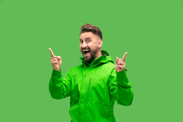 Handsome bearded smiling happy young man looking at front isolated on vivid trendy green studio