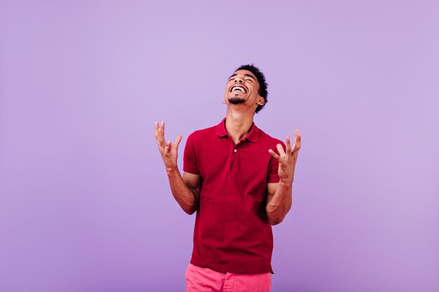 Handsome black guy expressing happiness. carefree dark-haired man in red shirt.
