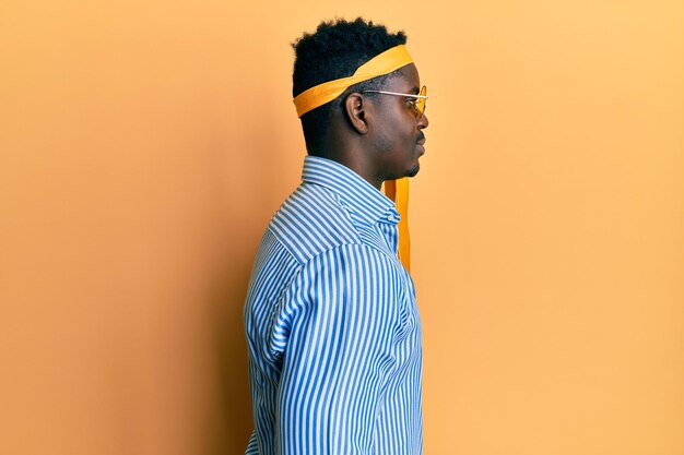 Handsome black man drunk wearing tie over head and sunglasses looking to side, relax profile pose with natural face with confident smile.