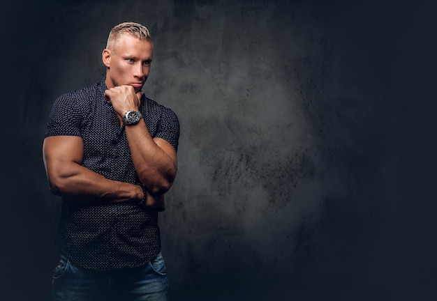 Free photo handsome blond man in a dark blue shirt posing over grey background in a studio.