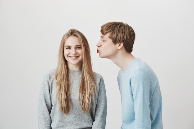 Handsome boyfriend asking for kiss, girl smiling camera in braces