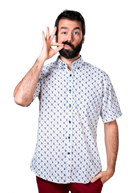 Handsome brunette man with beard making silence gesture