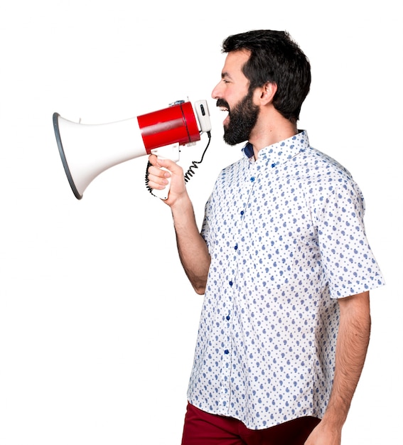 Handsome brunette man with beard shouting by megaphone