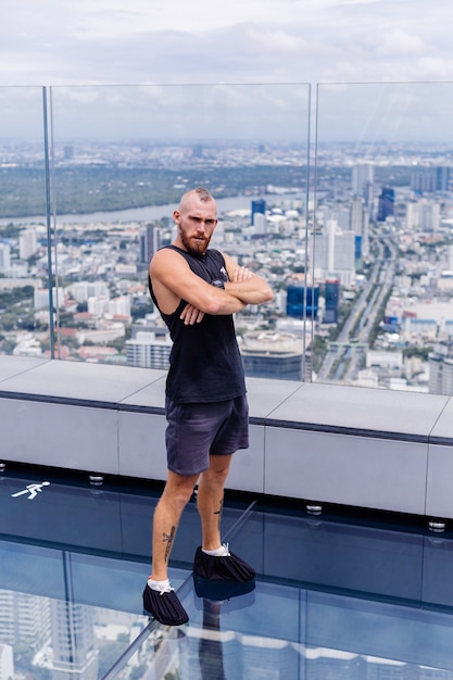 Handsome brutal bearded caucasian man on rd glass floor in Bangkok