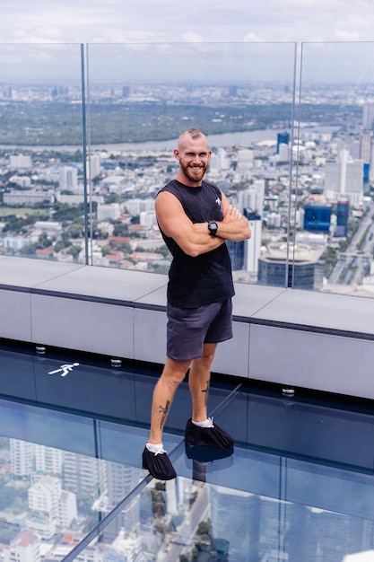 Free photo handsome brutal bearded caucasian man on rd glass floor in bangkok