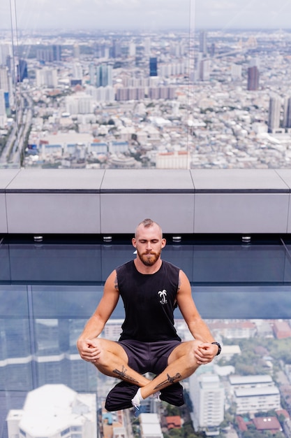 Free photo handsome brutal bearded caucasian man on rd glass floor in bangkok