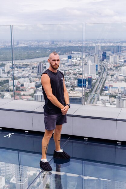 Handsome brutal bearded caucasian man on rd glass floor in Bangkok