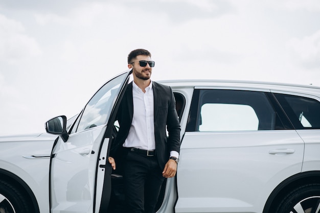 Free photo handsome business man by the white car