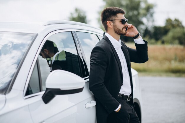 Handsome business man by the white car