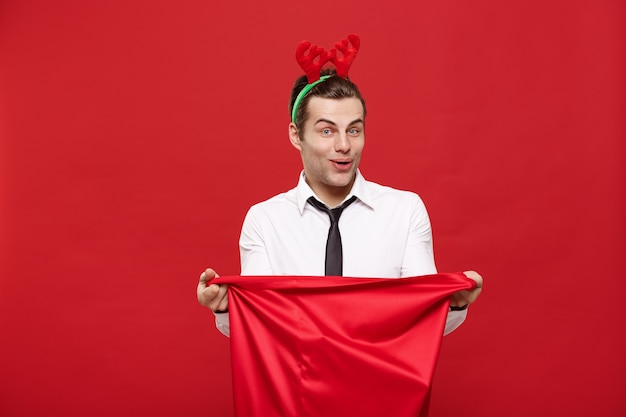 Handsome Business man celebrate merry christmas wearing reindeer hairband holding Santa red big bag.
