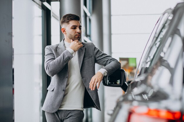 Handsome business man choosing a car in a car showroom