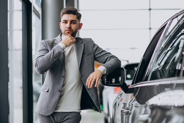 Handsome business man choosing a car in a car showroom