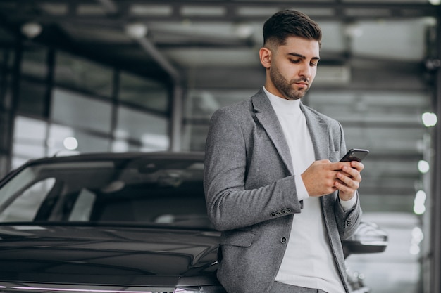 Handsome business man talking on the phone in a car showroom