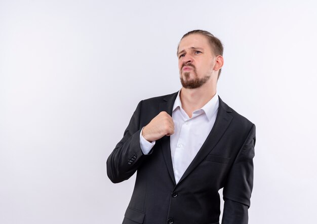 Handsome business man wearing suit looking aside with skeptic expression standing over white background