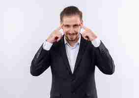 Free photo handsome business man wearing suit looking at camera with smile on face pointing his temples focused on task standing over white background