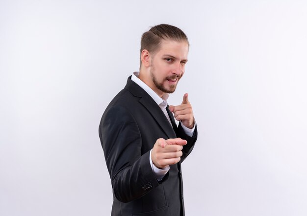 Handsome business man wearing suit looking confident pointing with fingers to camera standing over white background