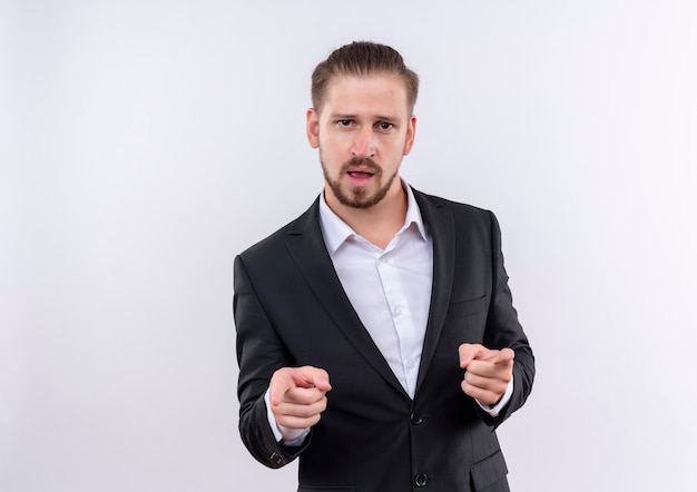 Handsome business man wearing suit looking confident pointing with index fingers to camera standing over white background