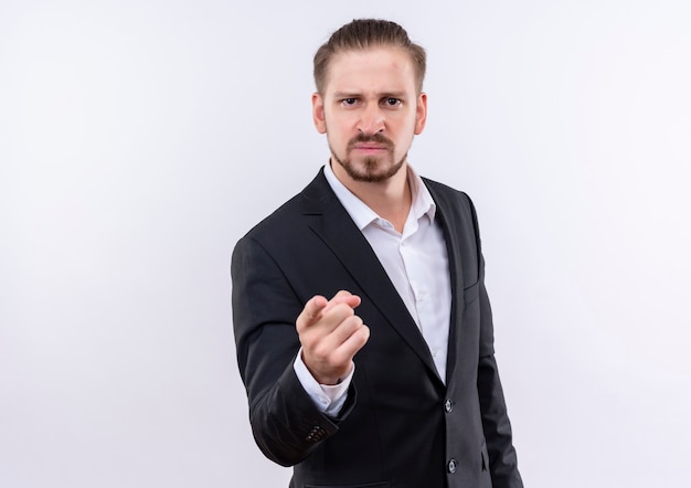 Handsome business man wearing suit pointing with finger to camera displeased standing over white background