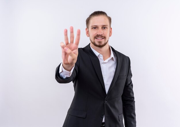 Handsome business man wearing suit showing and pointing up with fingers number three standing over white background