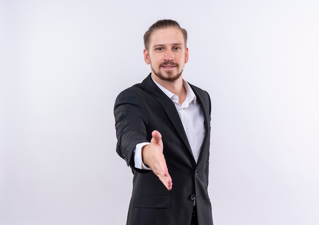 Free photo handsome business man wearing suit smiling friendly greeting offering hand standing over white background