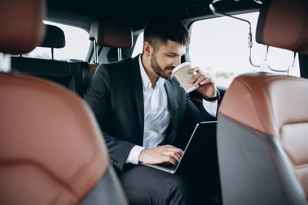 Handsome business man working on a computer in car