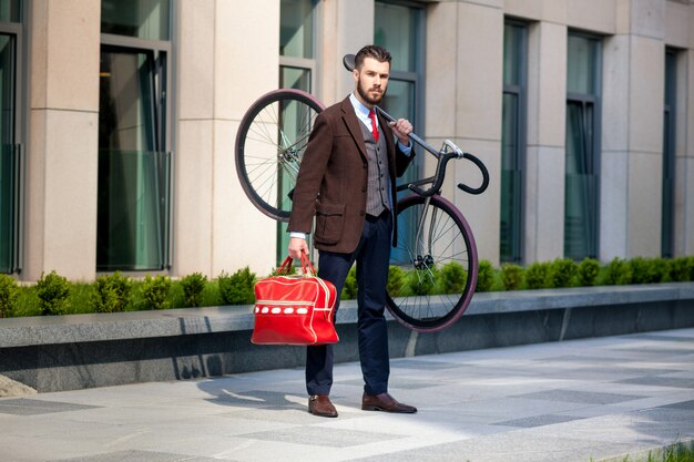 オフィスで彼の自転車を運ぶハンサムなビジネスマン