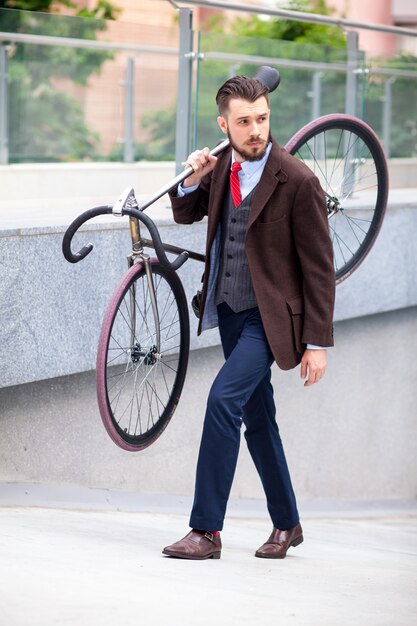 彼の自転車を運ぶハンサムなビジネスマン