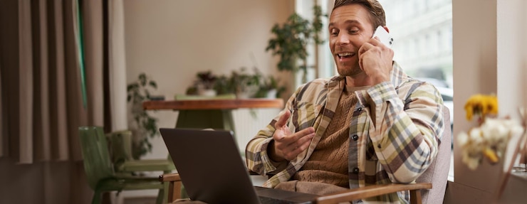 Free Photo handsome businessman in coffee shop sitting in cafe with laptop and calling someone man talking on the phone with client making enquiry about project talking to coworker while working remotely